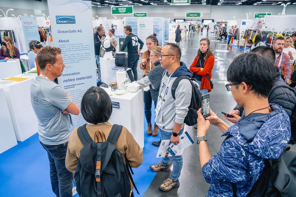 Functional Fabric Fair Fall visitors discussing materials at an exhibitor stand in 2023.