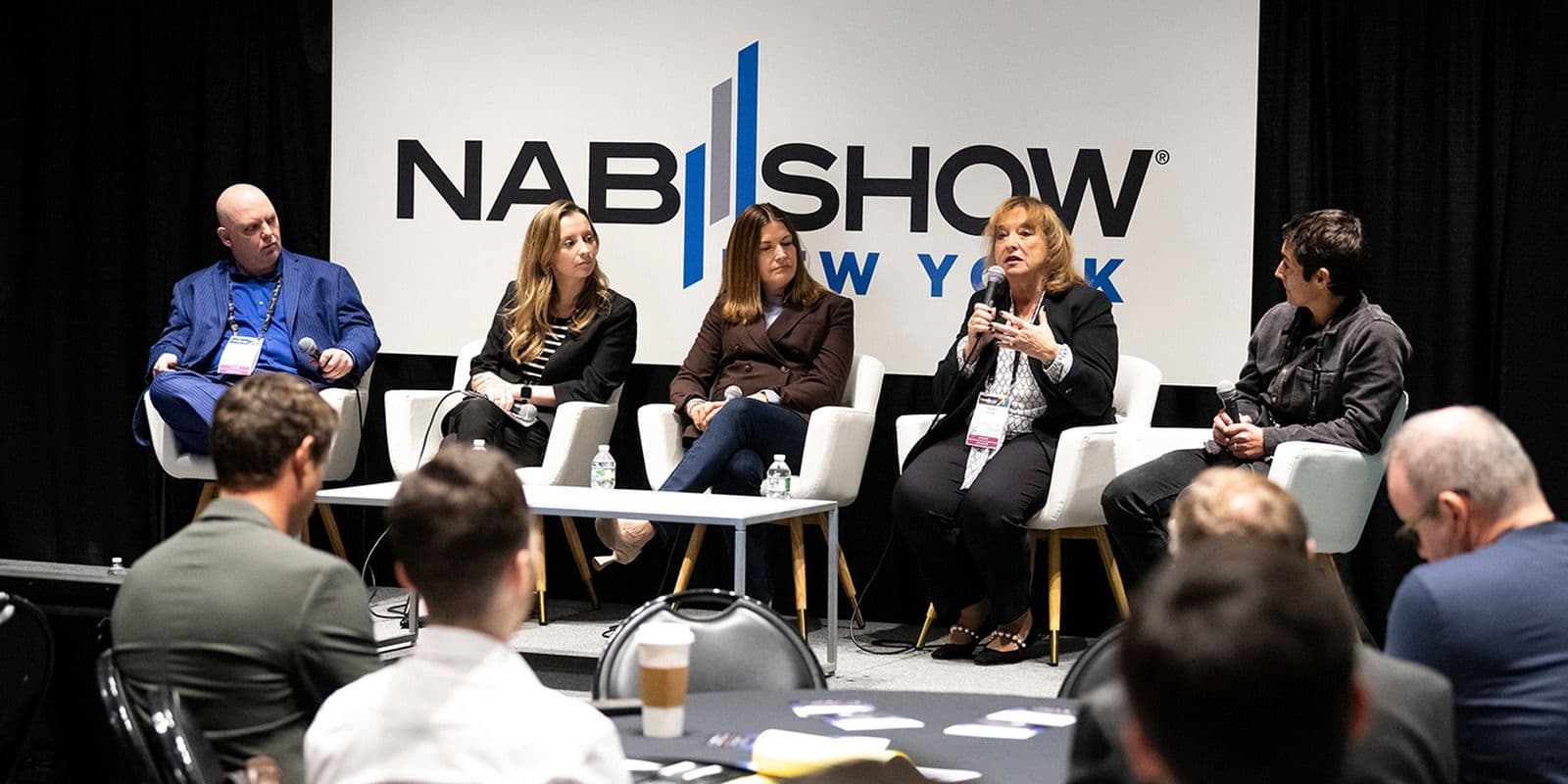 Five speakers in a panel session beneath NAB Show New York signage in 2024
