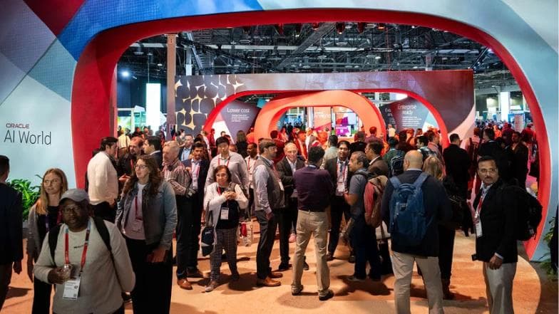 A packed keynote audience raising phones as large LED screens display visuals at Oracle AI World