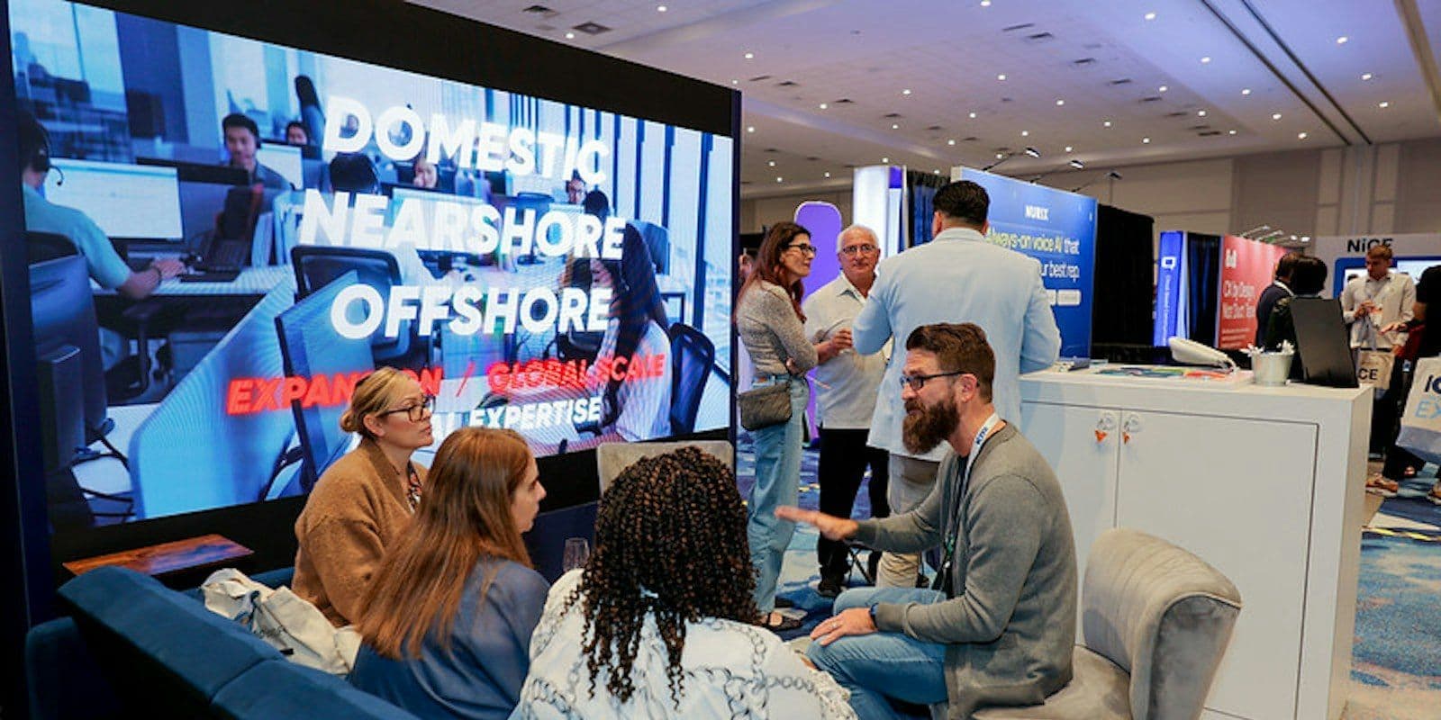 Attendees and an exhibitor discuss contact center operations at an ICMI expo booth.