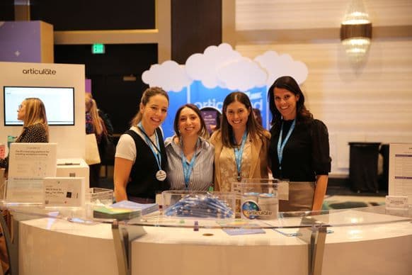 Four Articulate staff behind their booth at DevLearn 2025