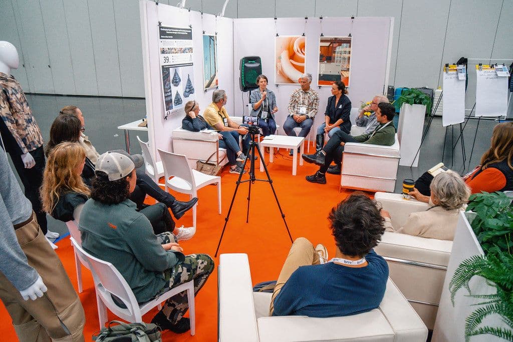Functional Fabric Fair Fall attendees listening to a panel discussion on the show floor in 2023.