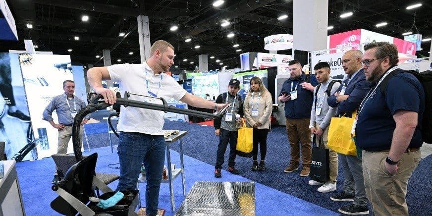 Exhibitor demonstrates a floor-cleaning machine to a group at the 2024 ISSA Show North America