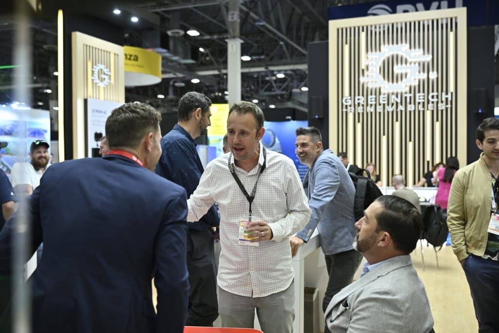 Clean energy professionals network near the GreenTech Renewables booth at RE+ 25