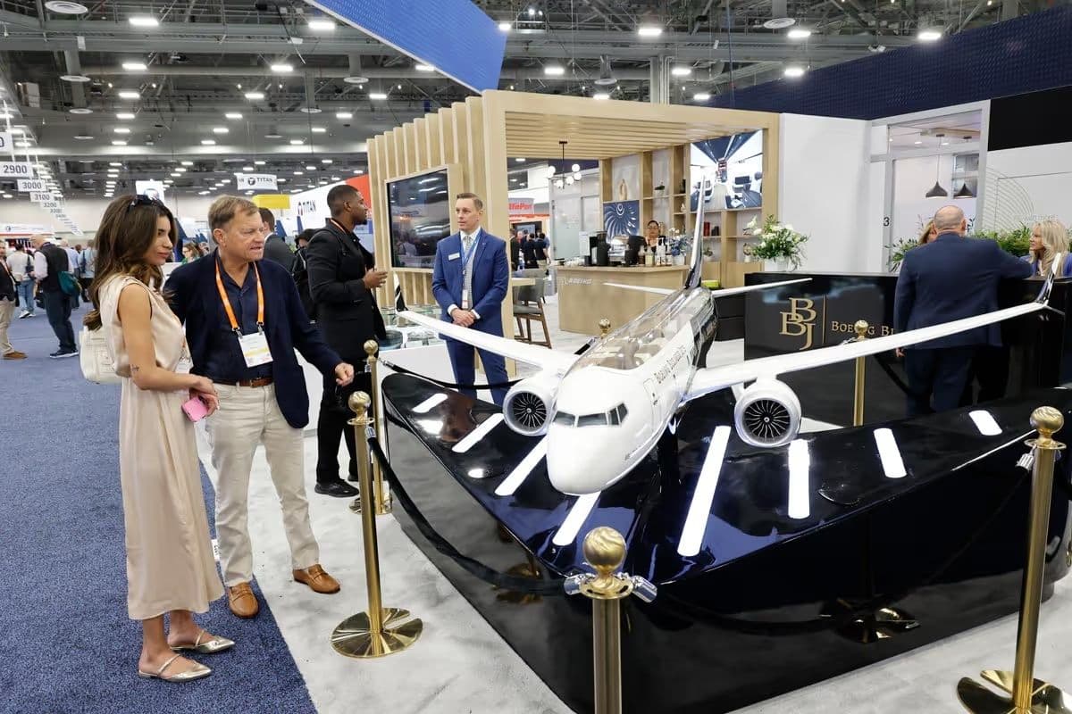Attendees examining an aircraft model on the 2025 NBAA-BACE show floor