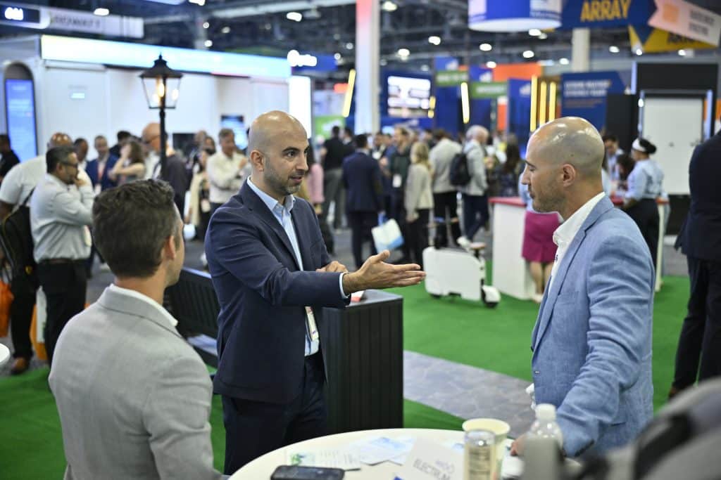 Two attendees talk in an exhibitor booth aisle at RE+ 25 in Las Vegas
