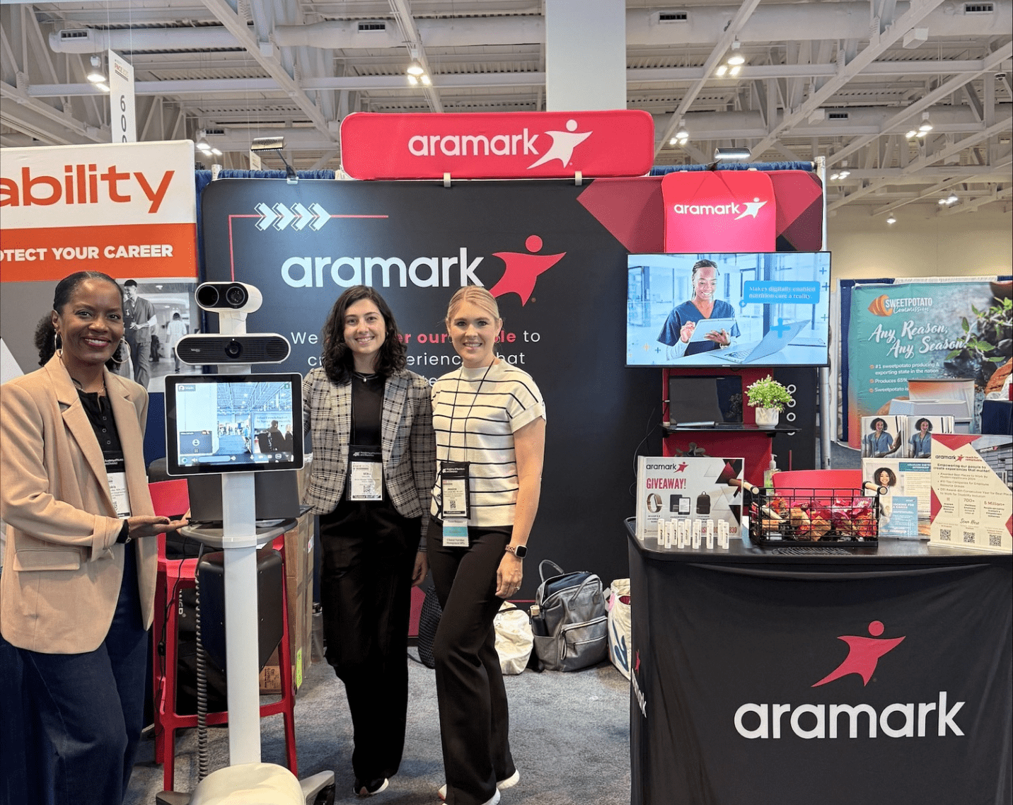 Three Aramark dietitians at their technology demonstration booth on the FNCE 2025 expo floor