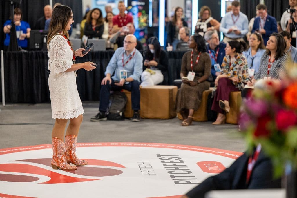 Presenter speaking to an audience in the Pitchfest area at HR Tech 2025