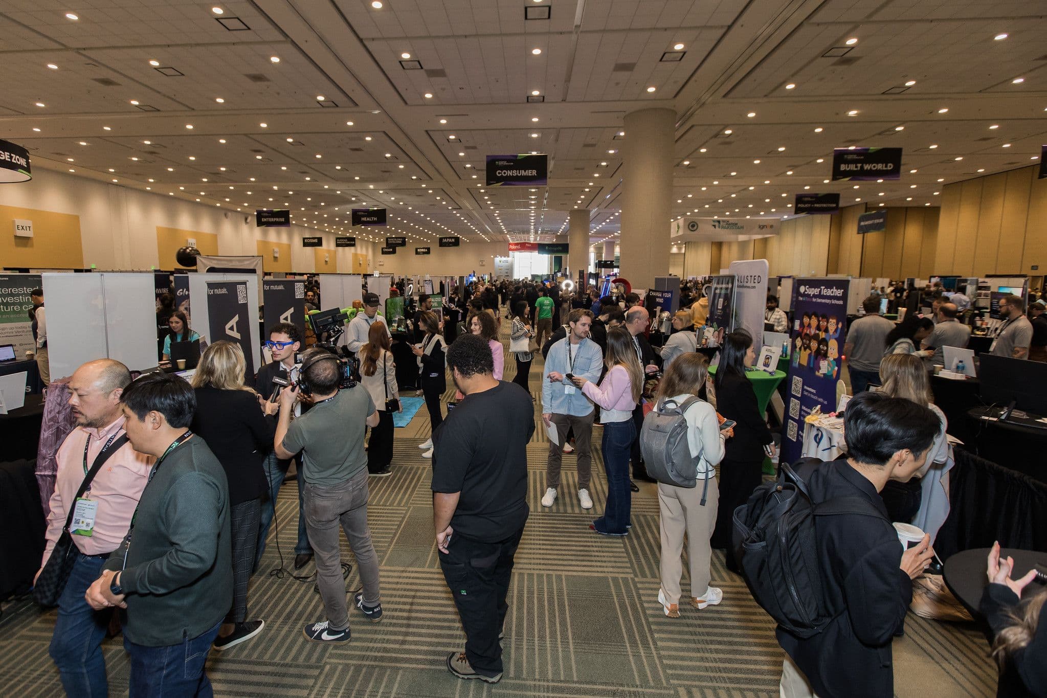 Attendees and startup booths across the TechCrunch Disrupt 2025 expo floor, with Consumer, Enterprise and Built World zone ba