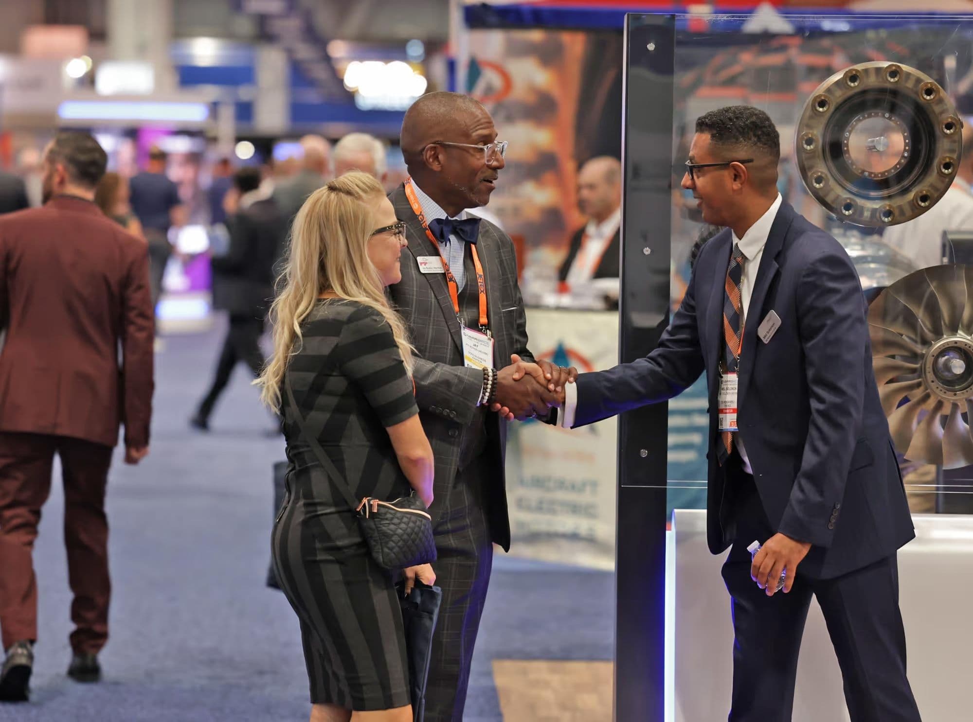 Attendees in conversation beside an aircraft component exhibit at 2025 NBAA-BACE