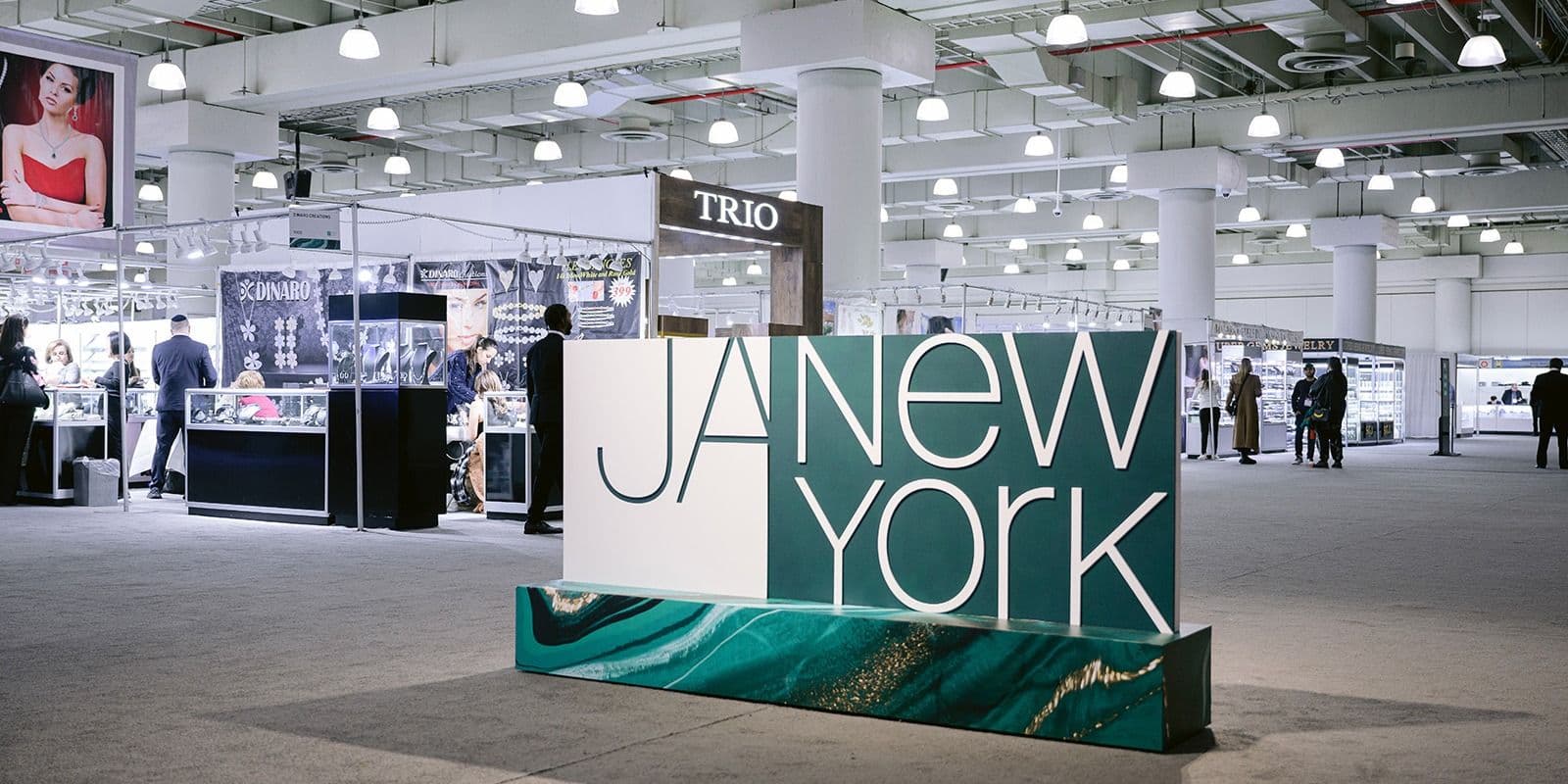 A wide view of the JA New York Spring 2024 show floor with booths and the event sign.