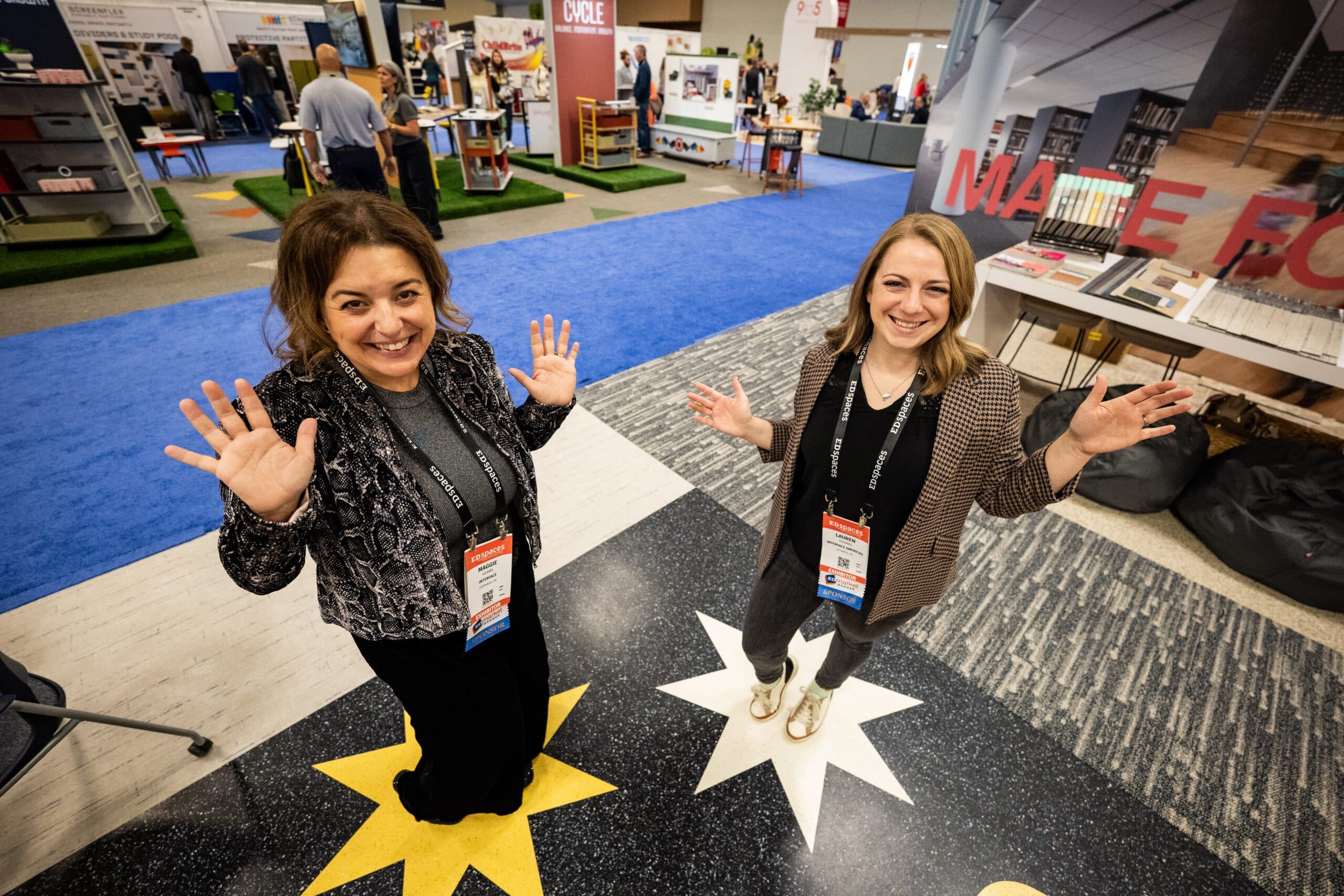 Two attendees greeting the camera on the EDspaces exhibit floor